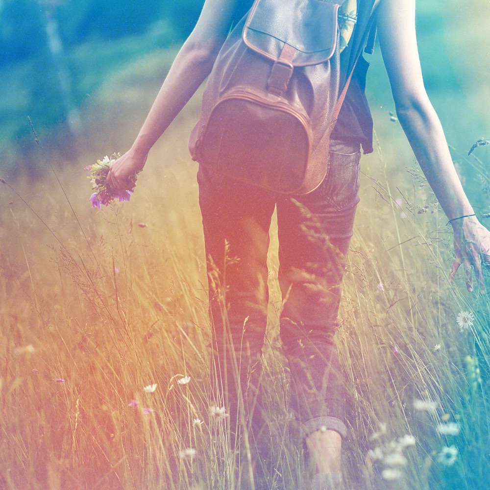 dreamlike image of woman walking throught a field of wild flowers